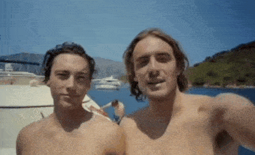 two shirtless men are standing next to each other on a boat .