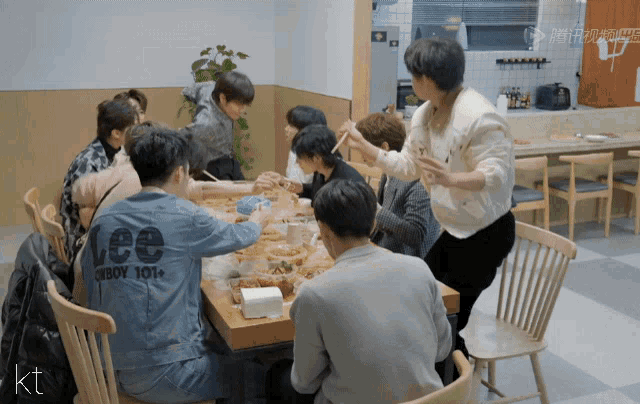 a group of people sitting around a table with one wearing a denim jacket that says lee