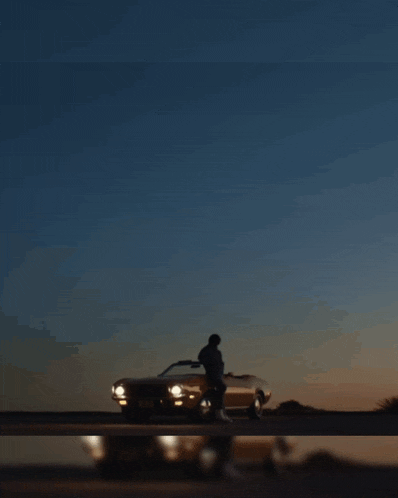 a man in a hoodie is standing on a balcony at sunset