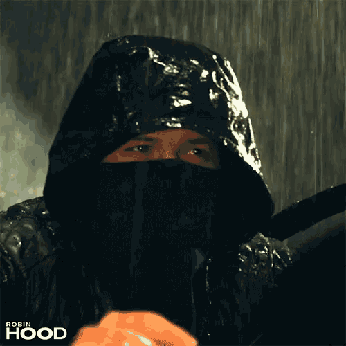 a man wearing a black hooded jacket with the word robin hood on the bottom right