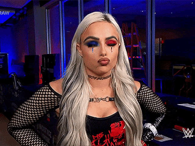 a woman with a choker on her neck is standing in front of a wwe logo