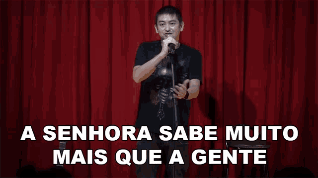 a man singing into a microphone with the words " a senhora sabe muito mais que a gente " above him