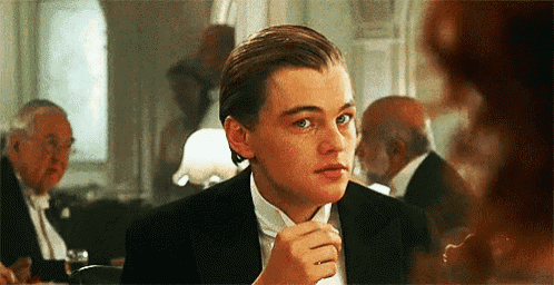 a man in a tuxedo and bow tie is sitting at a table with other people .