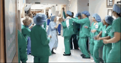 a group of nurses in green scrubs are dancing in a hospital hallway