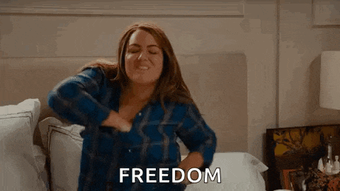 a woman is sitting on a bed with her arms outstretched and the word freedom written on the bottom .