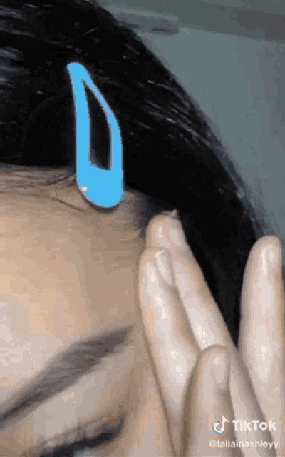 a close up of a woman 's face with a blue hair clip on it