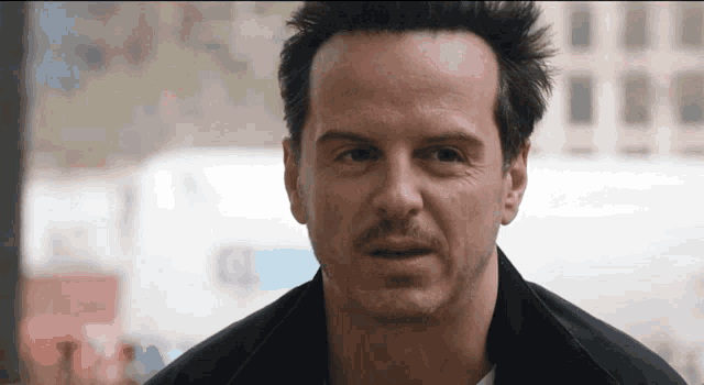 a man with a mustache looks at the camera with a serious look on his face