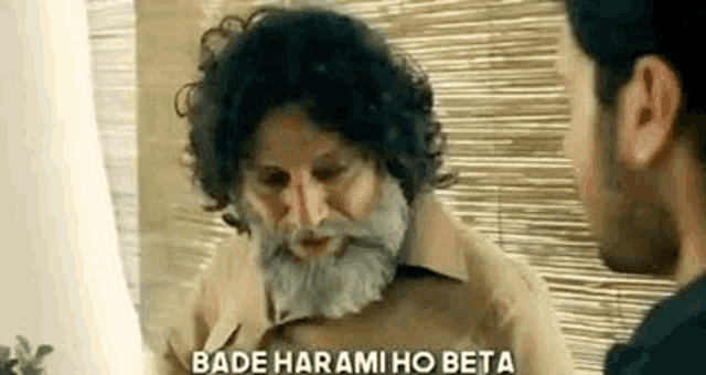 an older man with a beard and curly hair is talking to a younger man .