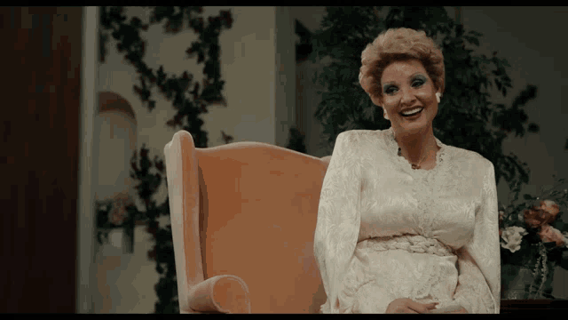 a woman in a white dress sits in a chair