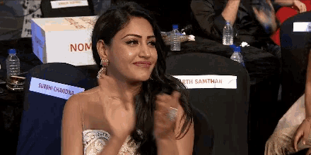 a woman applauds in front of a box that says nom on it
