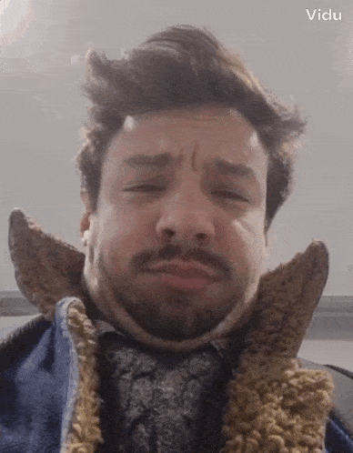 a man with a beard is wearing a neck brace and making a face .