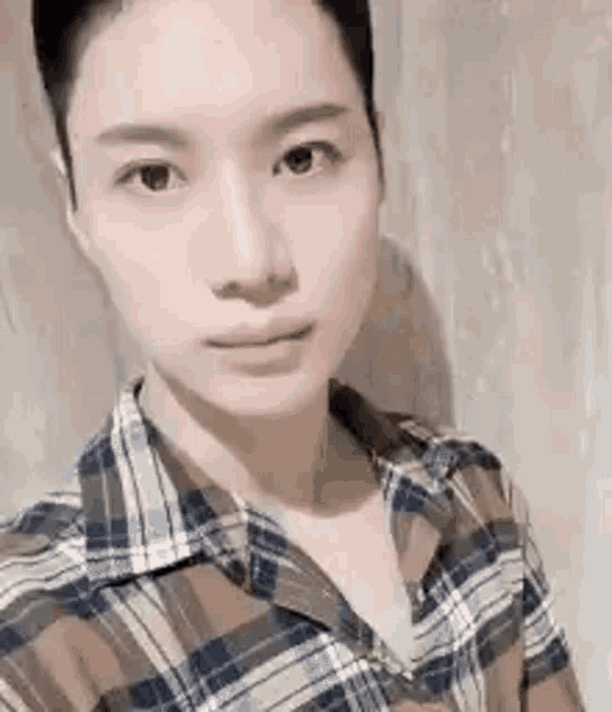 a woman in a plaid shirt is taking a selfie with her phone .
