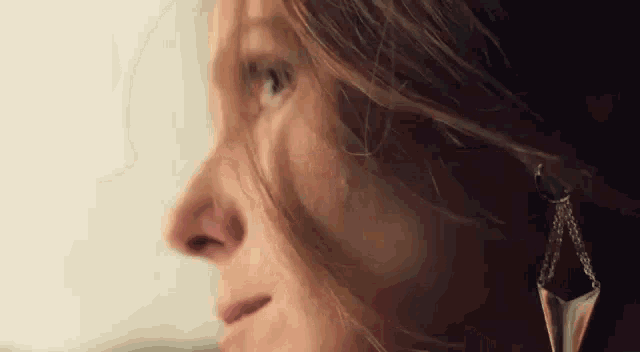 a close up of a woman 's face with long hair and earrings on .