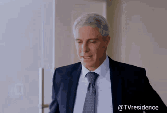 a man in a suit and tie is standing in front of a door with the hashtag @tvresidence