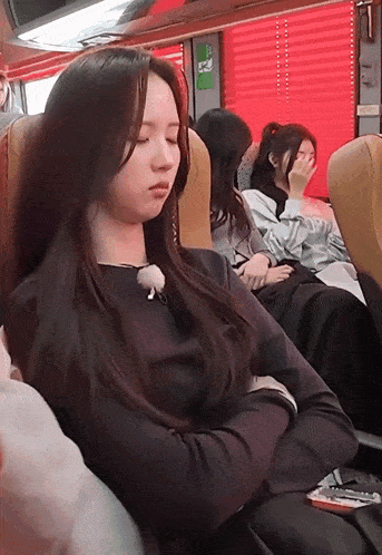 a woman sleeping on a bus with her eyes closed and a phone in her hand