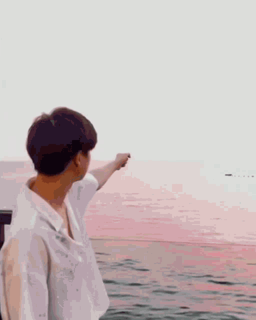 a man in a white shirt is standing on a beach with his arms outstretched .