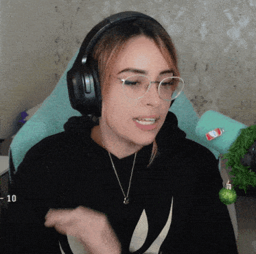 a woman wearing headphones and glasses is sitting in front of a christmas tree