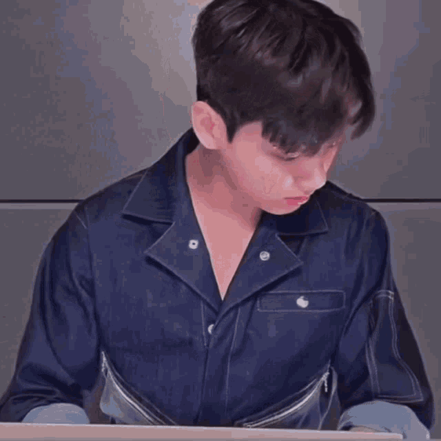a man in a denim jacket is sitting at a table