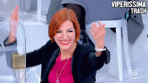 a woman in a pink top and black jacket is smiling and waving with the words viperissima trash behind her