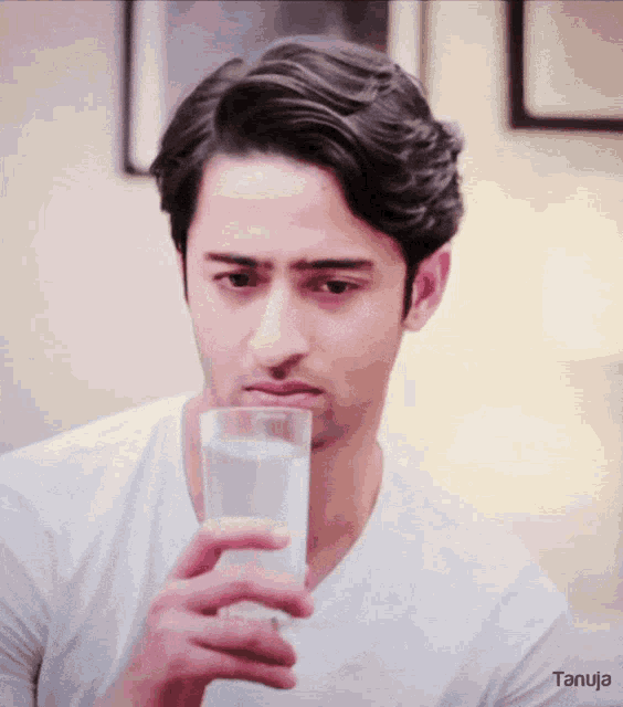 a man in a white shirt is drinking a glass of water from a tanuja ad