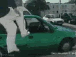 a man in white pants is jumping out of a green car .