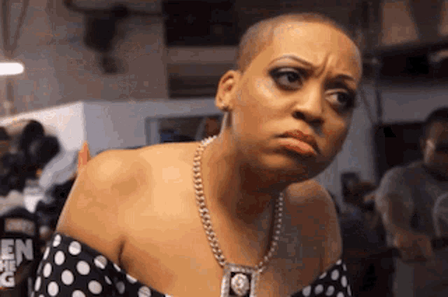 a woman wearing a polka dot dress and a necklace has a serious look on her face ..