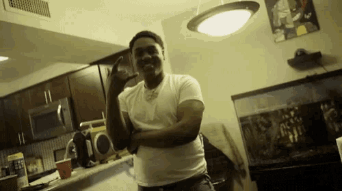 a man in a white shirt stands in a kitchen with his arms crossed