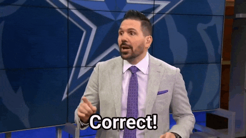 a man in a suit and tie says correct in front of a large screen