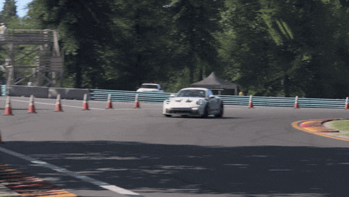 a white race car is driving on a track with cones