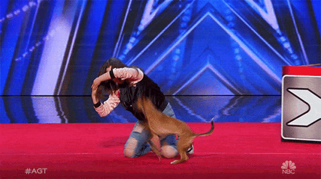 a woman kneeling down with a dog on a red carpet that says #agt on the bottom