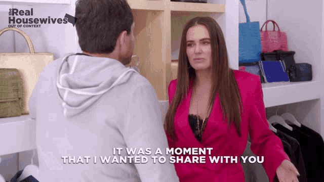 a woman in a pink jacket is talking to a man in a grey hoodie in a real housewives ad