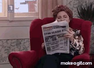 a woman sitting in a red chair reading a newspaper
