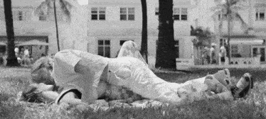 a black and white photo of a couple laying on the grass
