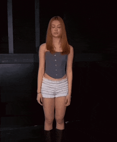 a woman with red hair is wearing shorts and a grey top
