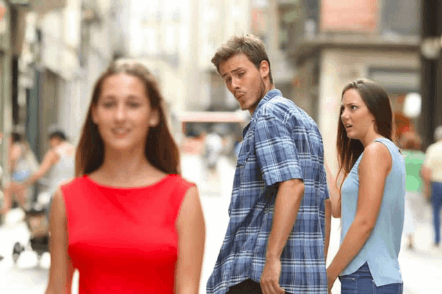 a man in a plaid shirt is walking down the street while a woman in a red dress looks on