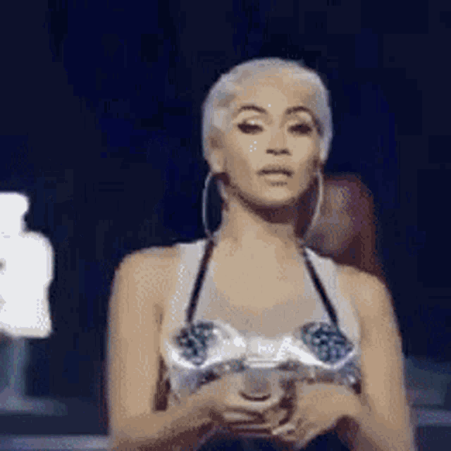a woman in a bra is holding a microphone in her hand .