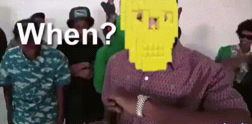a group of men are standing in a room and one of them is wearing a yellow spongebob mask on his face .