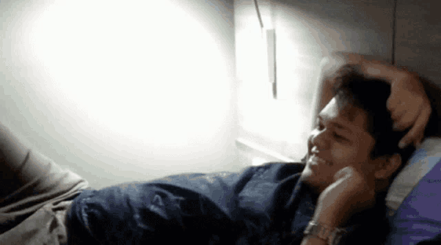 a man is laying on a bed with his hands on his head