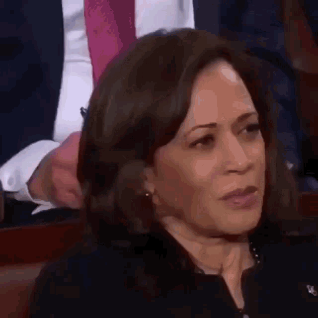 a close up of a woman sitting in a chair with a man in a suit and tie behind her .