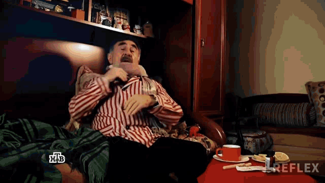 a man in a striped shirt is sitting on a couch with a cup of coffee in front of a reflex logo