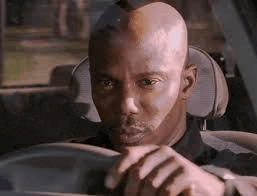 a man with vitiligo is driving a car and looking at the camera .