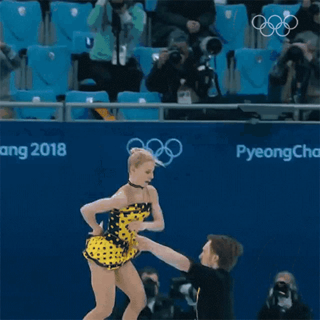 a man and a woman are skating in front of a sign that says pyeongchang 2018 on it