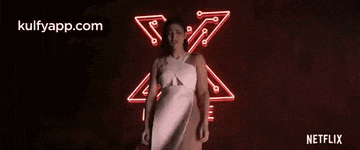 a woman is standing in front of a red neon sign .