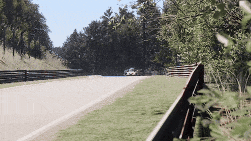 a race car is driving down a track with trees on the side