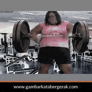 a woman in a pink shirt is lifting a barbell