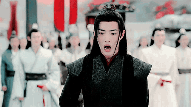 a man in a black robe stands in front of a crowd