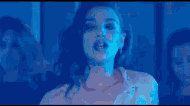 a woman is standing in front of a crowd of people in a dark room in a blue light .