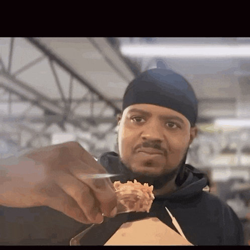 a man wearing a black headband is holding a piece of food in his hand