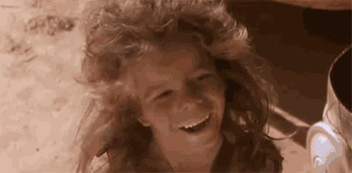 a young girl with long curly hair is smiling .