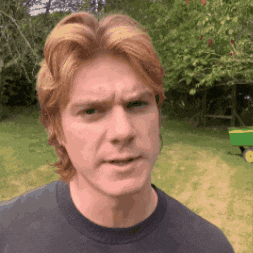 a man with red hair is wearing a black shirt and making a face